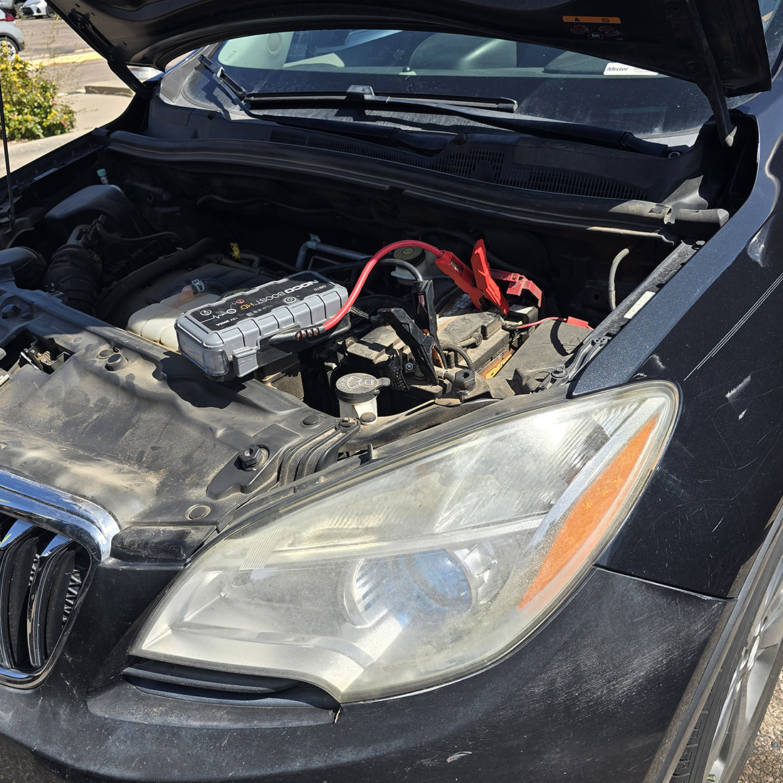 Car being jump-started in Santa Fe, NM by JQ Towing using a portable booster pack