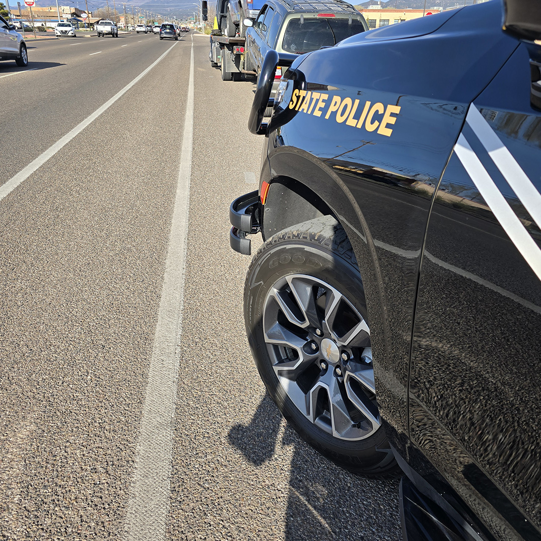New Mexico State Police with vehicle transport trailer stopped on the shoulder of a highway